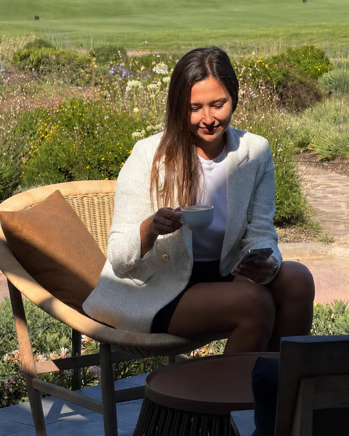 Olga Bondareva tomando un café al aire libre mientras revisa contenido en el móvil